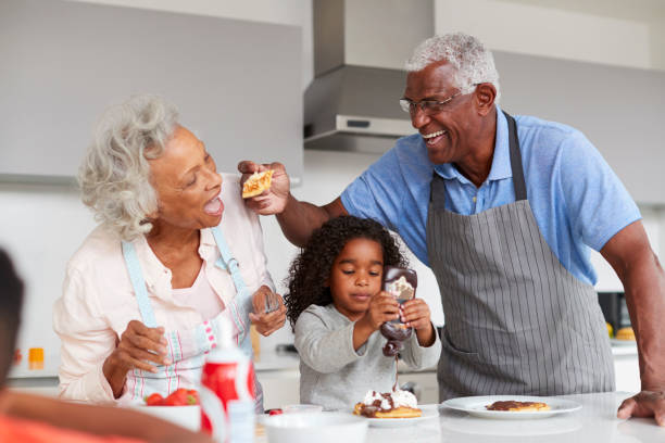 großeltern in küche mit großmutter machen pfannkuchen zusammen - oma kocht stock-fotos und bilder