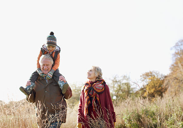 grandparents walking outdoors with grandson - happy couple cold stockfoto's en -beelden