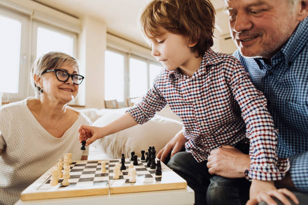 Grandson playing chess against grandma Boy and grandfather playing chess together against gradmother board game photos stock pictures, royalty-free photos & images