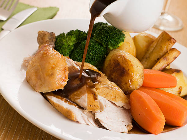 Gravy being Poured over a plate of Roast Chicken Gravy being Poured over a plate of Roast Chicken and Vegetables roast dinner stock pictures, royalty-free photos & images
