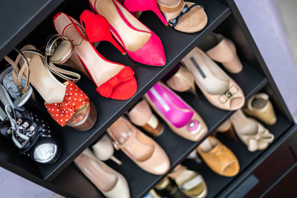 Gray closet shelves full of fashion female shoes on heels pair storage organization of cupboard stock photo