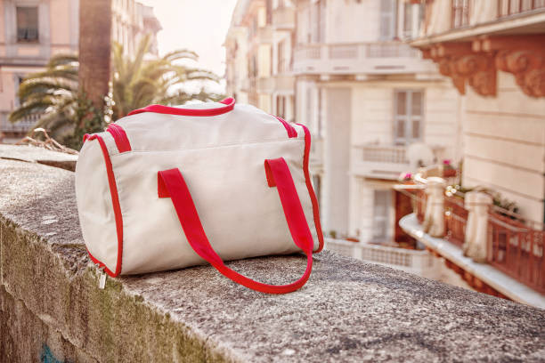 borsa bagagli grigia con linee rosse si trova sulla ringhiera in pietra della città vecchia italiana di la spezia - milan spezia foto e immagini stock
