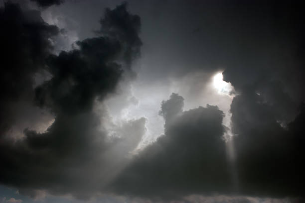 Photo of gray storm clouds through which the sun looks out