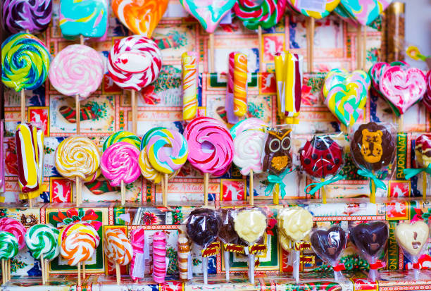 Great choice of colorful caramel on stick and chocolate candy for sale in shop window Great choice of colorful caramel different shapes on stick and chocolate candy for sale in shop window candy store stock pictures, royalty-free photos & images