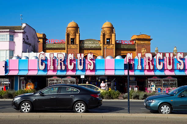 Great Yarmouth's Hippodrome Circus Great Yarmouth, England - September 28, 2011: Holiday-makers stroll along Marine Parade, Great Yarmouth, Norfolk, in the late September sunshine, outside an amusement arcade with circus signs. The Hippodrome Circus is the only surviving dedicated circus building in the UK and dates from 1903. The circus runs for two months every summer holiday season, attracting international acts. An unusual feature is its aquatic event, with synchronised swimmers, at the end of each circus show. The building, which is like a miniature Albert Hall inside, stages many other events out-of-season. great yarmouth front stock pictures, royalty-free photos & images