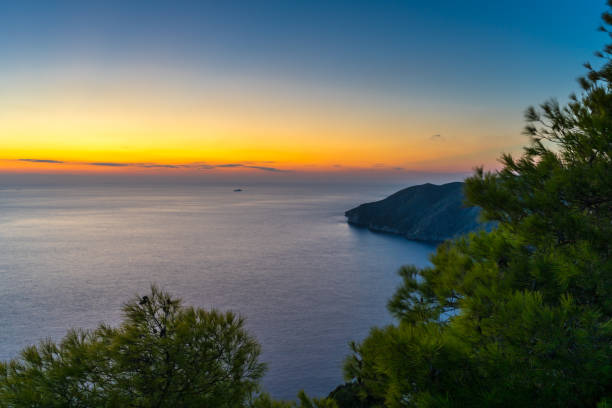Photo of Greece, Zakynthos, Endless silent ocean and cliff behind green trees in blue hour