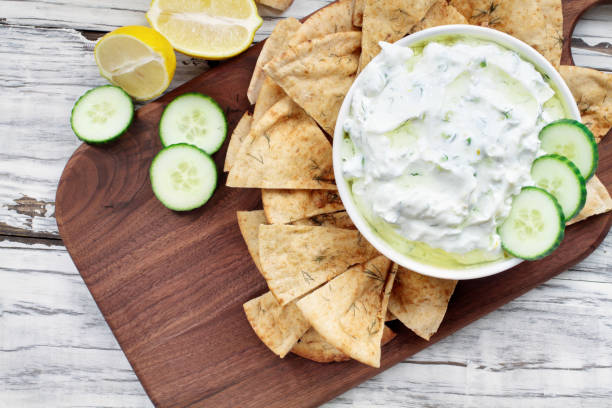 Greek Tzatziki dip sauce Traditional Greek Tzatziki dip sauce made with cucumber sour cream, Greek yogurt, lemon juice, olive oil and a fresh sprig of dill weed. Served with toasted Za'atar Pita bread.  Top view  or flat lay. dipping sauce stock pictures, royalty-free photos & images