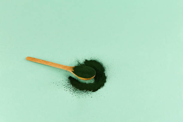 Green algae in powder - chlorella, spirulina in spoon Green algae in powder - chlorella, spirulina in spoon  on light background. green algae stock pictures, royalty-free photos & images