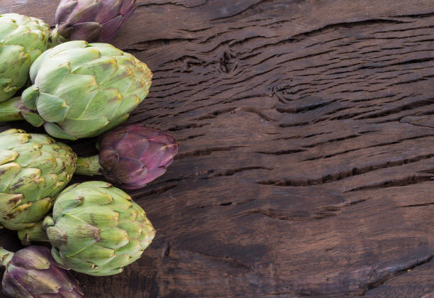green and purple artichoke flower edible buds on wooden background. - artichoke tea 個照片及圖片檔