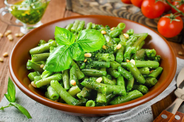Green beans with pesto and pine nuts Green beans with pesto and pine nuts. Delicious balanced food concept green bean stock pictures, royalty-free photos & images