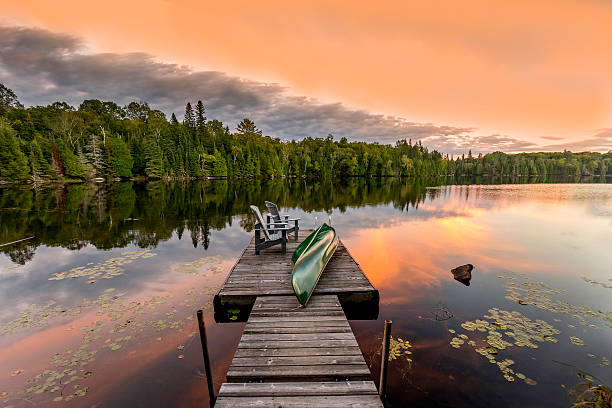 Green Canoe and Chairs on a Dock at Sunset stock photo