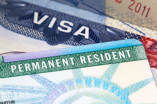 green card macro shot of a US green card with a passport visa in the background passport stamp stock pictures, royalty-free photos & images