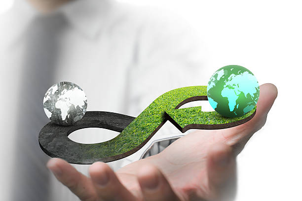 Green circular economy concept Green circular economy concept. Man's hand showing arrow infinity symbol with grass texture and two globes of different colors. circular economy stock pictures, royalty-free photos & images