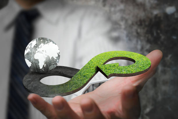 Green circular economy concept Green circular economy concept. Hand showing arrow infinity symbol with grass texture and globe. circular economy stock pictures, royalty-free photos & images