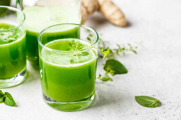 Green detox juice with ginger and mint in glasses and jars. stock photo