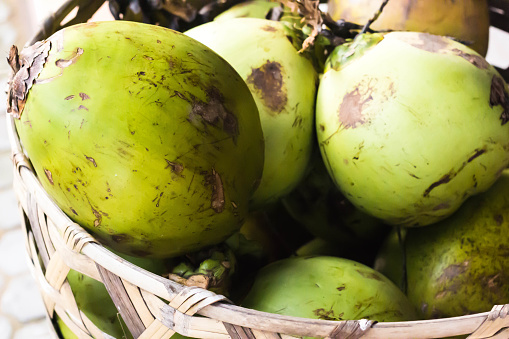Green Fresh Coconuts in Woven Basket.