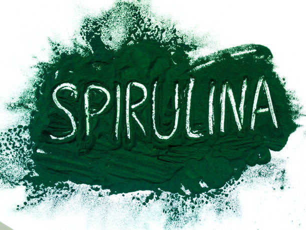 spirulina hawaii hijau dalam bubuk dengan prasasti spirulina pada latar belakang putih muda. makanan super, gaya hidup sehat, konsep suplemen sehat - spirulina potret stok, foto, & gambar bebas royalti