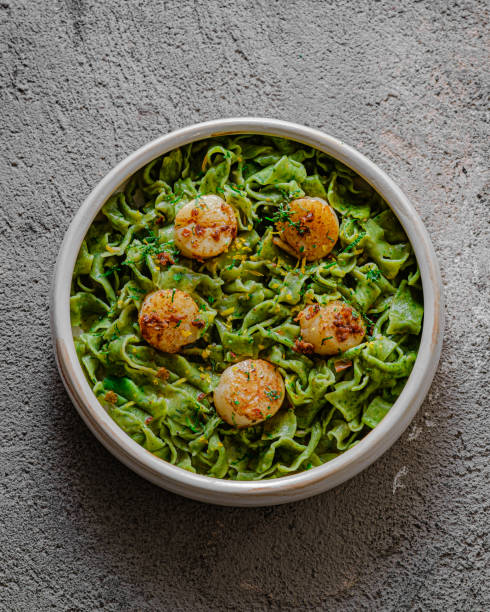 Green homemade spinach pasta with scallops and sauce, close view stock photo