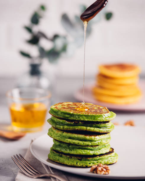 Green pancakes with matcha tea or spinach, dressed honey and red grapes. Healthy breakfast with superfoods. Light background, hugge scandinavian style stock photo
