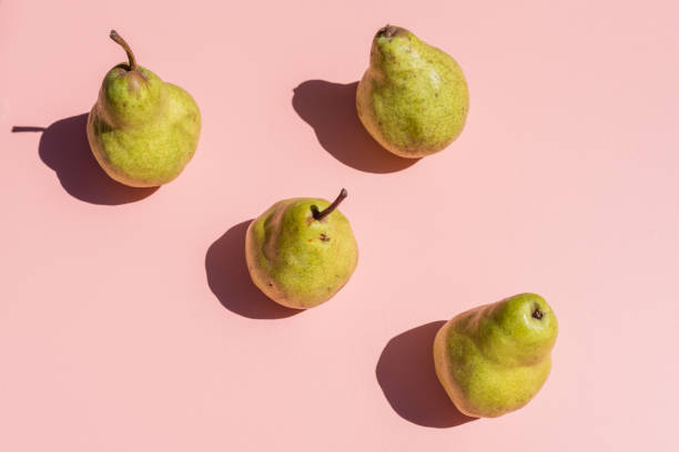 Green pears on pink background from above High angle view of green pears arranged on pink background with hard shadows from bright sunlight (selective focus) imperfection photos stock pictures, royalty-free photos & images