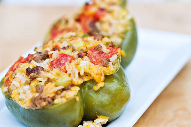 Green peppers stuffed with rice, cheese, meat and tomatoes Baked peppers stuffed with turkey burger, rice, tomatoes and cheddar cheese. Shallow DOF with focus on pepper in front.  stuffed bell peppers stock pictures, royalty-free photos & images