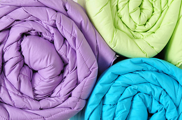 Green, purple, and blue duvet covers rolled up Close up of a colorful rolled up duvets. duvet photos stock pictures, royalty-free photos & images