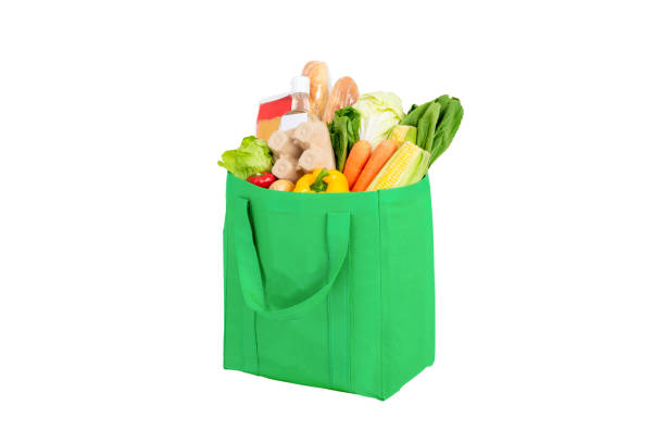 groene herbruikbare boodschappentas hoogtepunt van groenten en kruidenierswaren die op witte achtergrond wordt geïsoleerdn - boodschappentas tas stockfoto's en -beelden