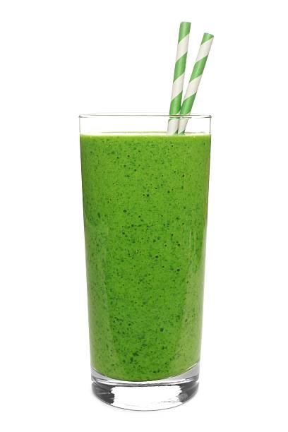 Green smoothie in glass with straws isolated on white Healthy green smoothie in a glass with paper straws isolated on a white background smoothie stock pictures, royalty-free photos & images