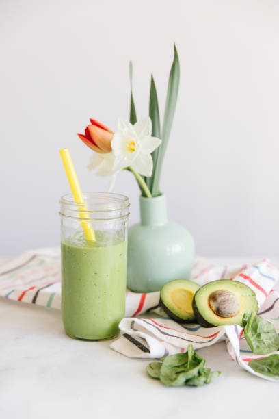 A green smoothie with flowers in the background stock photo
