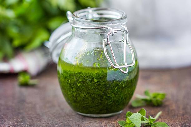 Green tasty herb sauce marinade from oregano, parsley, oil Green tasty herb sauce marinade from oregano, parsley, oil, traditional chimichuri in glass jar green olives jar stock pictures, royalty-free photos & images