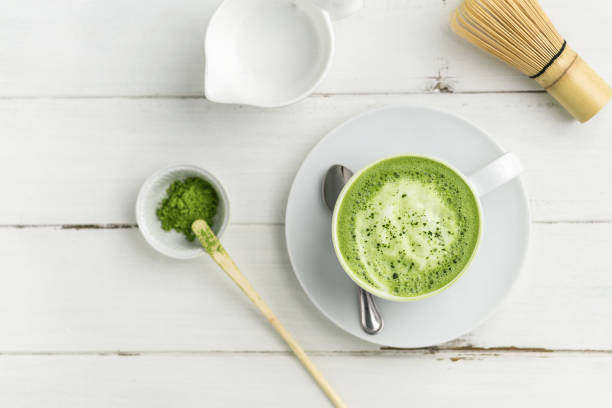 Green tea matcha latte cup on white background from above flat view. Matcha latte cup on white background from above. This latte is a delicious way to enjoy the energy boost & healthy benefits of matcha. Matcha is a powder of green tea leaves packed with antioxidants. latte stock pictures, royalty-free photos & images