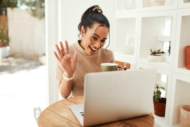 Greeting my followers in my new vlog Cropped shot of an attractive young businesswoman sitting and vlogging on her laptop while enjoying a cup of coffee small business saturday stock pictures, royalty-free photos & images