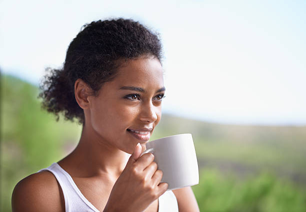 Greeting the morning sun with a smile Cropped shot of a young woman enjoying a cup of coffee curley cup stock pictures, royalty-free photos & images
