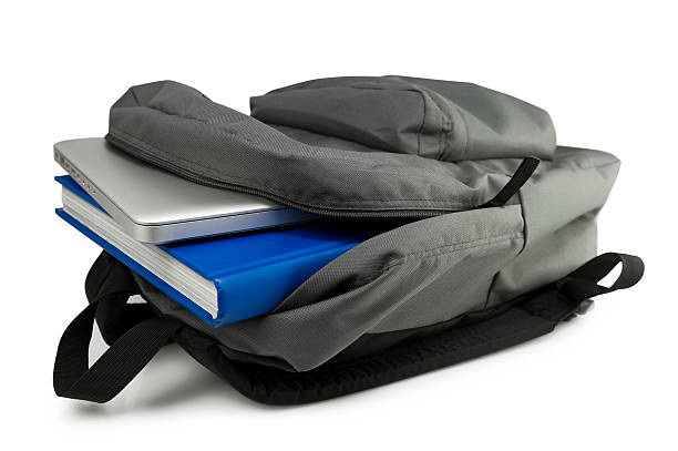 A grey backpack open to show a tablet and blue book stock photo
