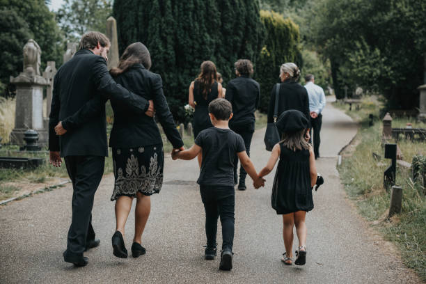 Grieving family walking through a cemetery stock photo