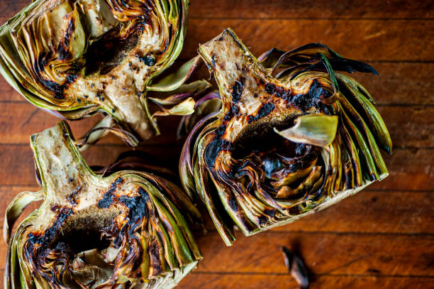 Grilled artichokes. Grilled artichokes. Fresh artichoke seasoned with salt and pepper and sautéed in olive oil, lemon juice and fresh herbs. Classic Italian fine dining restaurant appetizer. stock photo