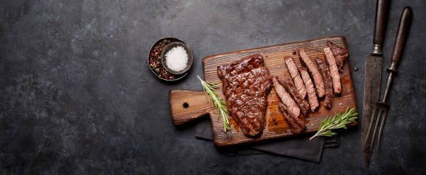 Grilled beef steak Grilled beef steak on wooden board. Top view flat lay with copy space cooked meat stock pictures, royalty-free photos & images
