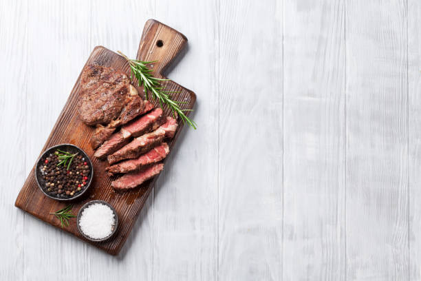 Grilled beef steak with spices on cutting board Grilled beef steak with spices on cutting board. Top view with copy space cooked meat stock pictures, royalty-free photos & images