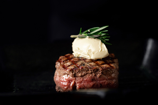 Grilled beef Tenderloin steak in a pan with butter on a dark background
