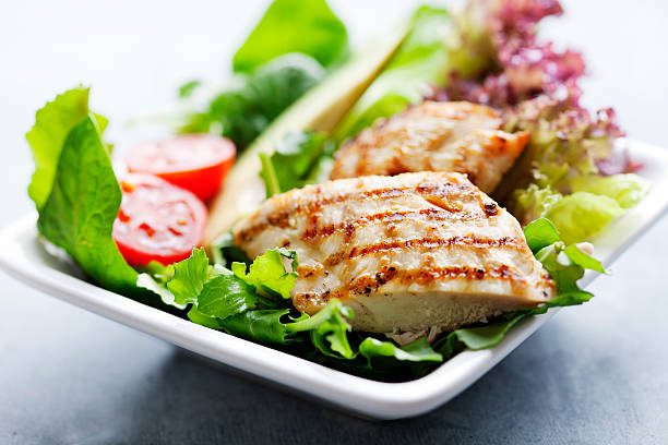 Grilled chicken breast on green salad stock photo