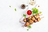 Grilled chicken kebab with red onions on a light table. Grilled meat skewers, shish kebab on light background. Top view, overhead, flat lay