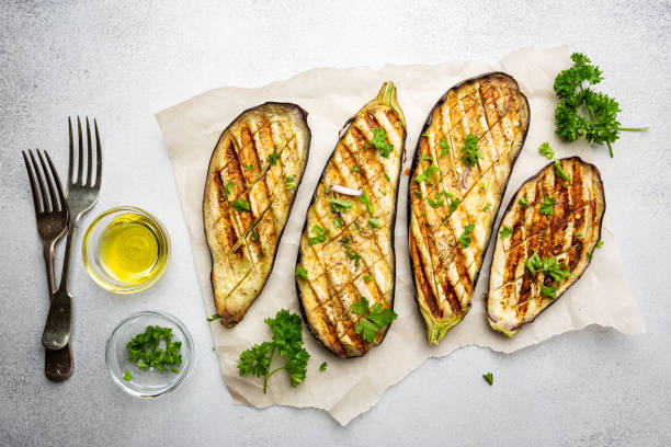 Grilled eggplant slices Grilled eggplant slices, garnished with fresh herbs, on white background, top view eggplant stock pictures, royalty-free photos & images