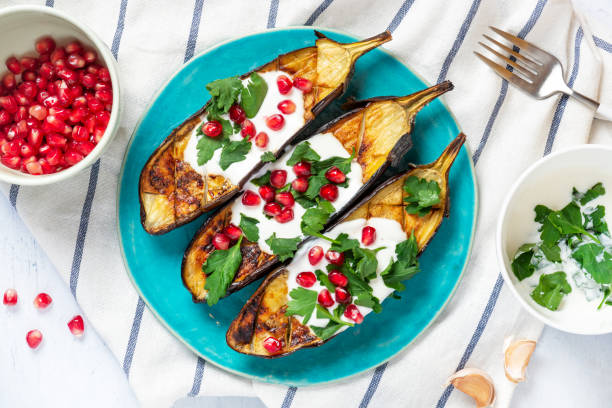 Grilled eggplant with yogurt, parsley, garlic and pomegranate on a blue ceramic plate Grilled eggplant with yogurt, parsley, garlic and pomegranate on a blue ceramic plate, top view. Healthy Mediterranean cuisine, vegetarian food. middle eastern culture stock pictures, royalty-free photos & images