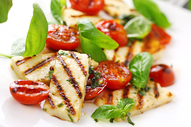Grilled halloumi cheese with roasted tomatoes and basil stock photo