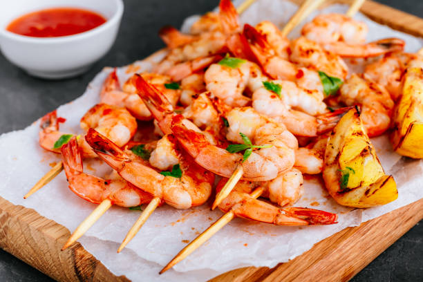 Grilled Lemon Shrimp Skewers in plate on gray stone background. Top view with copy space stock photo