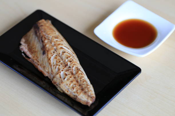 Grilled saba on black dish with dipping soy sauce and green spicy sauce stock photo