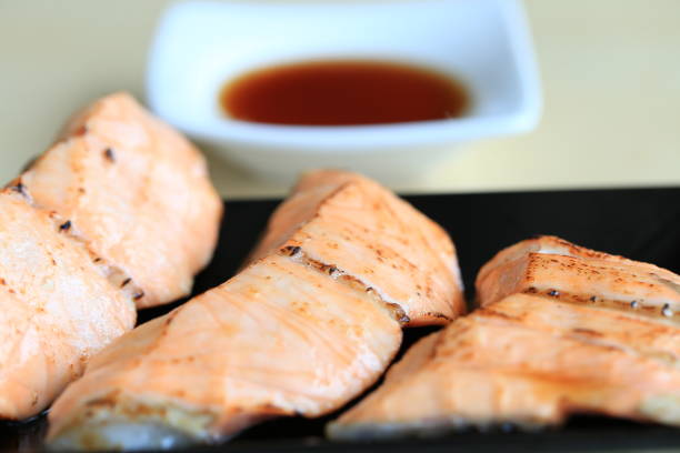 Grilled salmon on black dish with dipping soy sauce and green spicy sauce stock photo