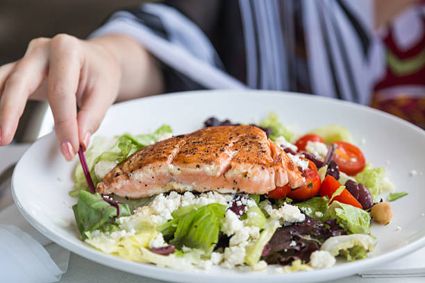 Grilled salmon salad. Grilled salmon salad with tomato, feta cheese, lettuce and so on and hand approaching. healthy dinner stock pictures, royalty-free photos & images
