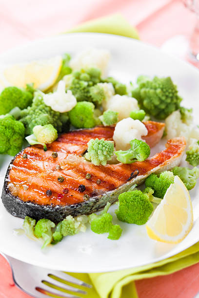 grilled salmon with broccoli and cauliflower on white plate stock photo