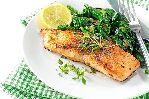 grilled salmon with thyme, lemon and spinach, vegetarian food grilled salmon with thyme, lemon and spinach on a plate, vegetarian low carb dish, green white napkin on a white background, selected focus, narrow depth of field lent stock pictures, royalty-free photos & images